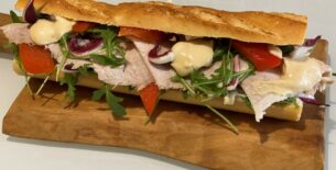 Baguette con noce di prosciutto marinata al miele e arancia, rucola, radicchio e peperoni abbrustoliti